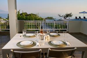 a table with plates and wine glasses on a balcony at Grand Villa Maronia in Platanitis Rodopis