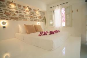 a white bed with purple flowers on top of it at Axilleion Boutique Hotel in Ermoupoli