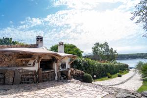 a stone house with a roof and a stone walkway at Villa Aratza in Orosei