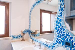 a bathroom with a blue and white mosaic mirror at Villa Aratza in Orosei +24 photos