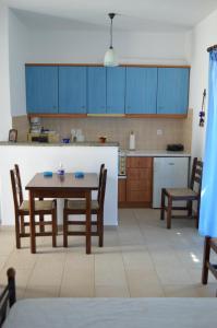 a kitchen with blue cabinets and a table and chairs at Karyatides Houses in Kariá