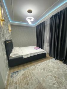 a bedroom with a bed in a room with a window at Апартамент Рахима Плаза2 in Shymkent