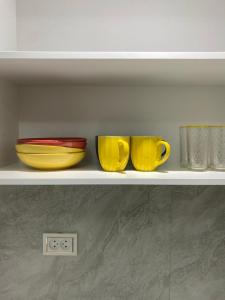 three yellow cups sitting on a shelf at Апартамент Рахима Плаза2 in Shymkent