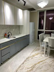 a kitchen with a sink and a refrigerator and a table at Апартамент Рахима Плаза2 in Shymkent