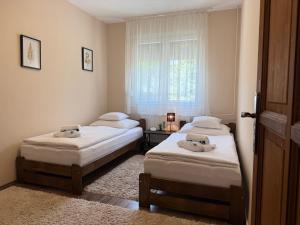 two beds in a small room with a window at City Edge Hideaway Apartment in Nagykanizsa +10 photos
