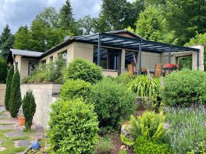 a house with a black awning in a garden at Ferienhaus Eifelgruß, in schöner Waldrandlage und tollem Naturgarten in Oberbettingen