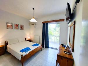 a bedroom with a bed and a television and a window at Alexia Apartments & Studios in Kremasti