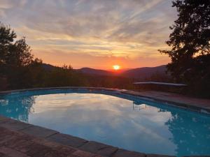 a swimming pool with the sunset in the background at Agriturismo Timignano in Monteguidi