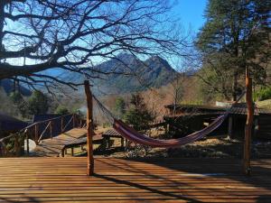 a hammock on a wooden deck with a mountain at KuyKuy Lodge in Malalcahuello
