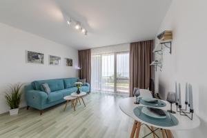 a living room with a blue couch and a table at Apartment Caricia complex Carpe Diem Balchik in Balchik