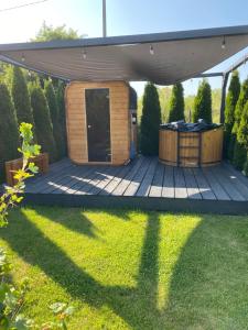 a wooden deck with a gazebo in a yard at Domek pod Sosnową Górą in Żelazno