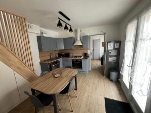 a kitchen with a wooden table and a dining room at La Maison Sable - Chaleureuse Familiale avec Jardin-300m de la plage in Ouistreham