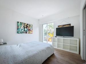 ein weißes Schlafzimmer mit Bett und Flachbildfernseher in der Unterkunft Beautiful luxury villa in Antibes