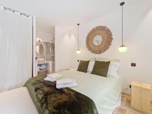 a white bedroom with a large bed with towels on it at Villa tout équipée - Piscine & pool house - CLIM in Uzès +42 photos