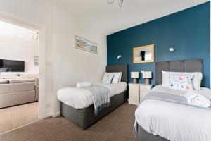 a bedroom with two beds and a blue wall at Sandy Seashells in Bournemouth