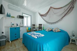 a bedroom with a blue bed and a kitchen at Casas da villa - Apartments in Ericeira