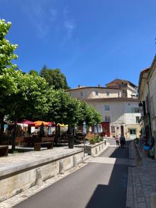 a street in a town with tables and umbrellas at Echoppe Ancienne Boutique de cordonnier avec jardin privé in Aubeterre-sur-Dronne +19 photos