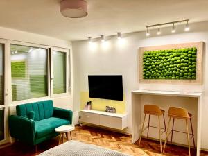 a living room with a green chair and a tv at Happy Sweet Apartment in Niš