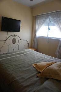 une chambre avec un grand lit avec une télévision au mur dans l'établissement Depto con balcón, pleno centro, à San Nicolás de los Arroyos