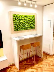 a painting of green grapes on a wall with two stools at Happy Sweet Apartment in Niš +10 photos