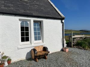 einen Stuhl vor einem Gebäude mit Fenster in der Unterkunft Skye Cottage - Vegan and Eco in Bernisdale