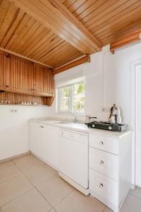 una cucina con mobili bianchi e soffitto in legno di Marmara Yali Evi a Isola di Marmara