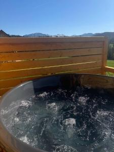 a bath tub filled with water next to a fence at Witowiańskie Domki z prywatnym jacuzzi i kominkiem in Dzianisz