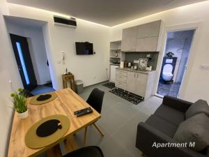 Una sala de estar con una mesa y una cocina. en Apartman M, en Belgrado