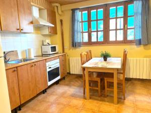 a kitchen with a table and a table and a microwave at Refugi acollidor de pedra i fusta by RURAL D'ÀNEU in Isavarre +1 photo