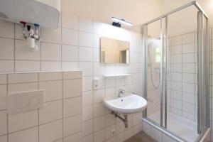 bagno bianco con lavandino e doccia di Nationalpark Gesäuse Lodge a Gstatterboden