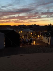 a group of people sitting at a table at sunset at Desert luxury tents in Merzouga +18 photos