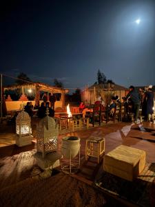 a group of people standing around a patio at night at Desert luxury tents in Merzouga
