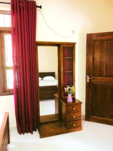 - une chambre avec un miroir, une commode et un lit dans l'établissement Peacock Kingdom, à Anurâdhapura