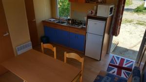 Una pequeña cocina con una mesa y un refrigerador. en Mobil-Home Clermont-Auvergne, en Sigean