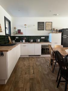 a kitchen with white cabinets and a wooden table at Maison Osithe in Doudeauville