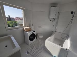 biała łazienka z pralką i oknem w obiekcie Apartments Mali Ivo w Nin +33 zdjęcia