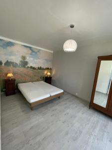 a bedroom with a bed and a painting on the wall at Les Coquelicots in Saint-Romain-sur-Cher