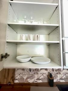 a white shelf with plates and glasses on it at Apartman Cañas Zelená Víla in Rimavská Sobota +10 photos