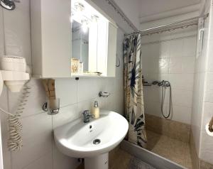 a white bathroom with a sink and a shower at Fabrika Apartments in Vári +19 photos
