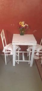 a white table with a vase of flowers and two chairs at فرينة in Essaouira