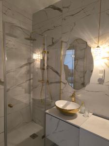 een badkamer met een wastafel en een glazen douche bij GoldClass Apartament in Katowice