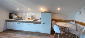 a kitchen with white cabinets and a table with white chairs at Mieszkanko z tarasem in Limanowa