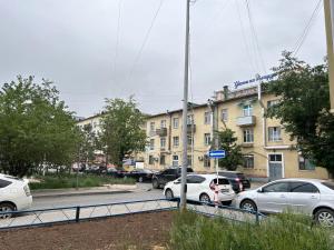 a parking lot with cars parked in front of a building at Sunny Hostel Mongolia in Ulaanbaatar