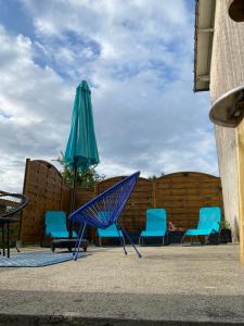a blue chair and an umbrella next to some chairs at Domaine De Domingeal Meublé de Tourisme 3 étoiles in Saint-Germain-les-Vergnes