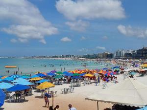 a beach with many umbrellas and people in the water at Brisa Do mar Apartamento 2 in Cabo Frio
