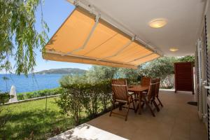 a patio with a table and chairs and a view of the water at Apartments Niana with heated swimingpool in Okrug Donji
