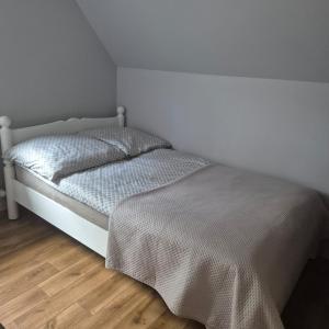 a white bed in a room with a wooden floor at Apartament GRZEŚ in Wielen Zaobrzanski
