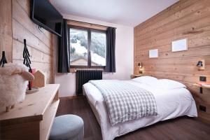 a bedroom with a bed and a desk and a television at Hôtel le Christiania in Arêches-Beaufort
