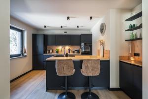 kuchnia z czarnymi szafkami i 2 stołkami barowymi w obiekcie Chalet Bergblick - Luxury Escape w mieście Bad Kleinkirchheim