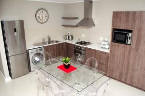 cocina con mesa de cristal con sillas y reloj en Mayfair Luxury Apartments, en Ciudad del Cabo